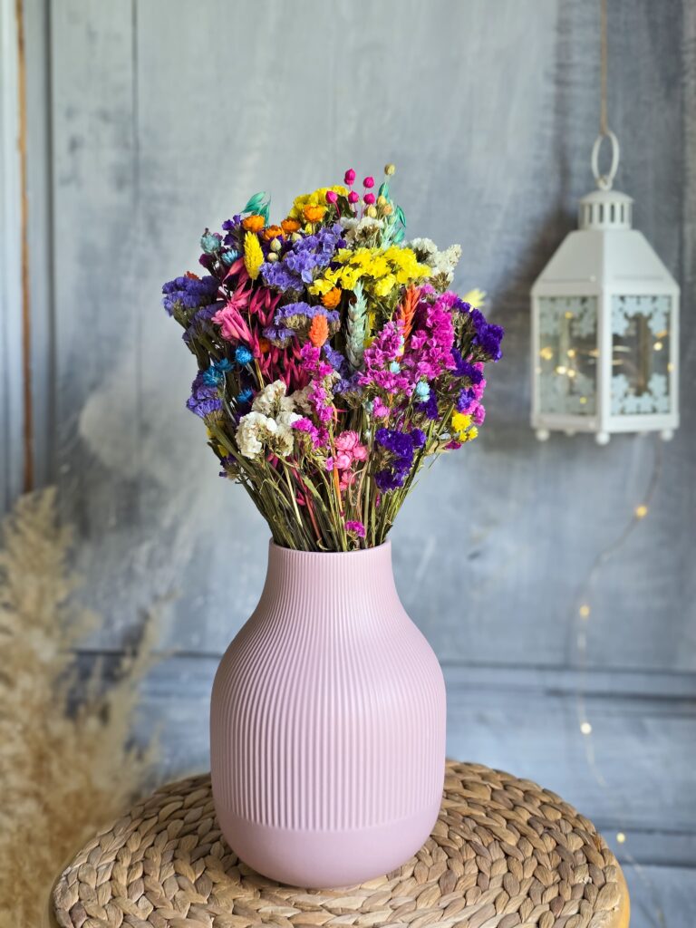 Kolorowy bukiet suszonych kwiatów i zbóż w różowym wazonie