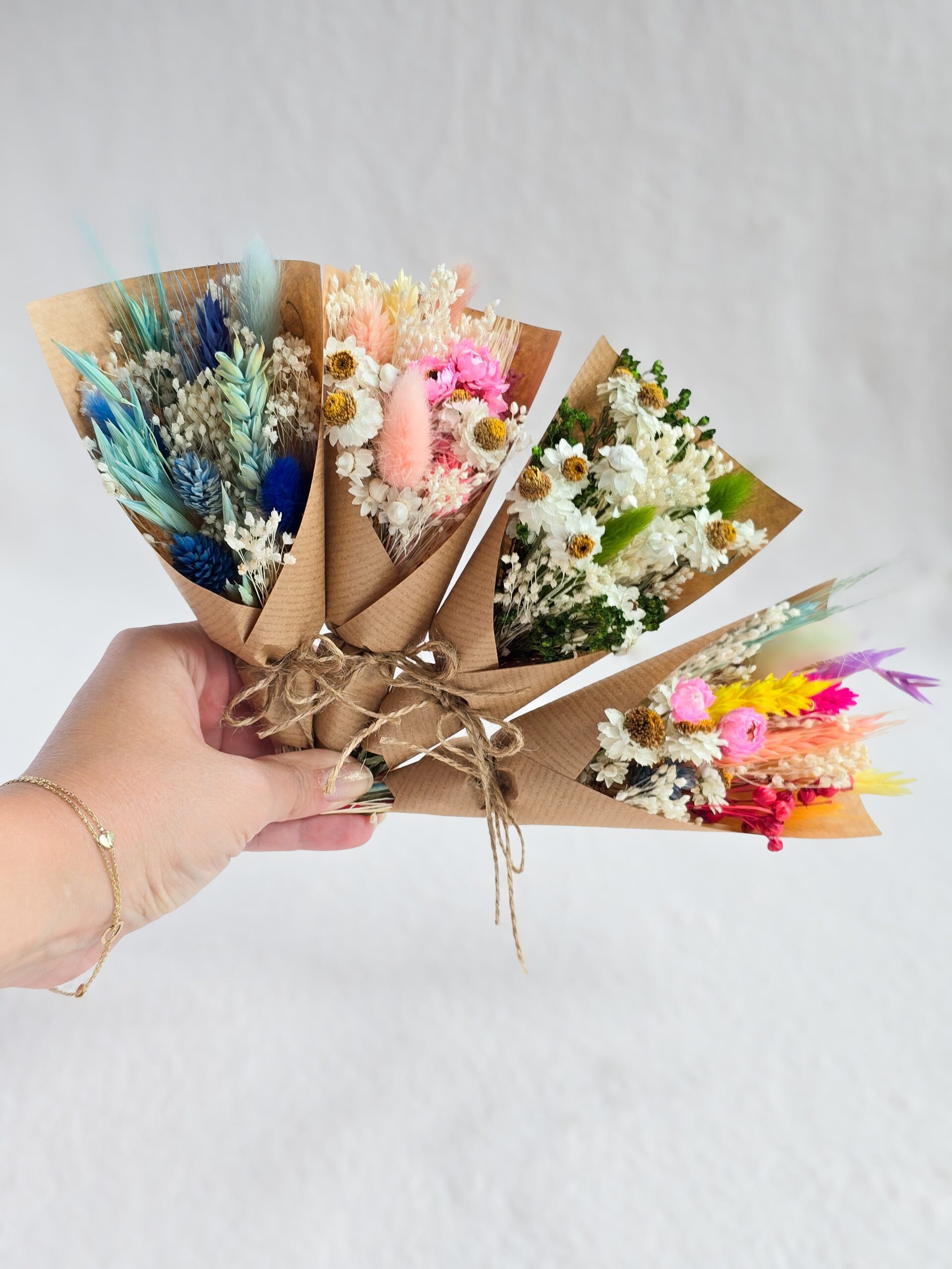 Małe bukieciki z suszonych kwiatów owinięte w papier kraft jako forma podziękowania dla gości