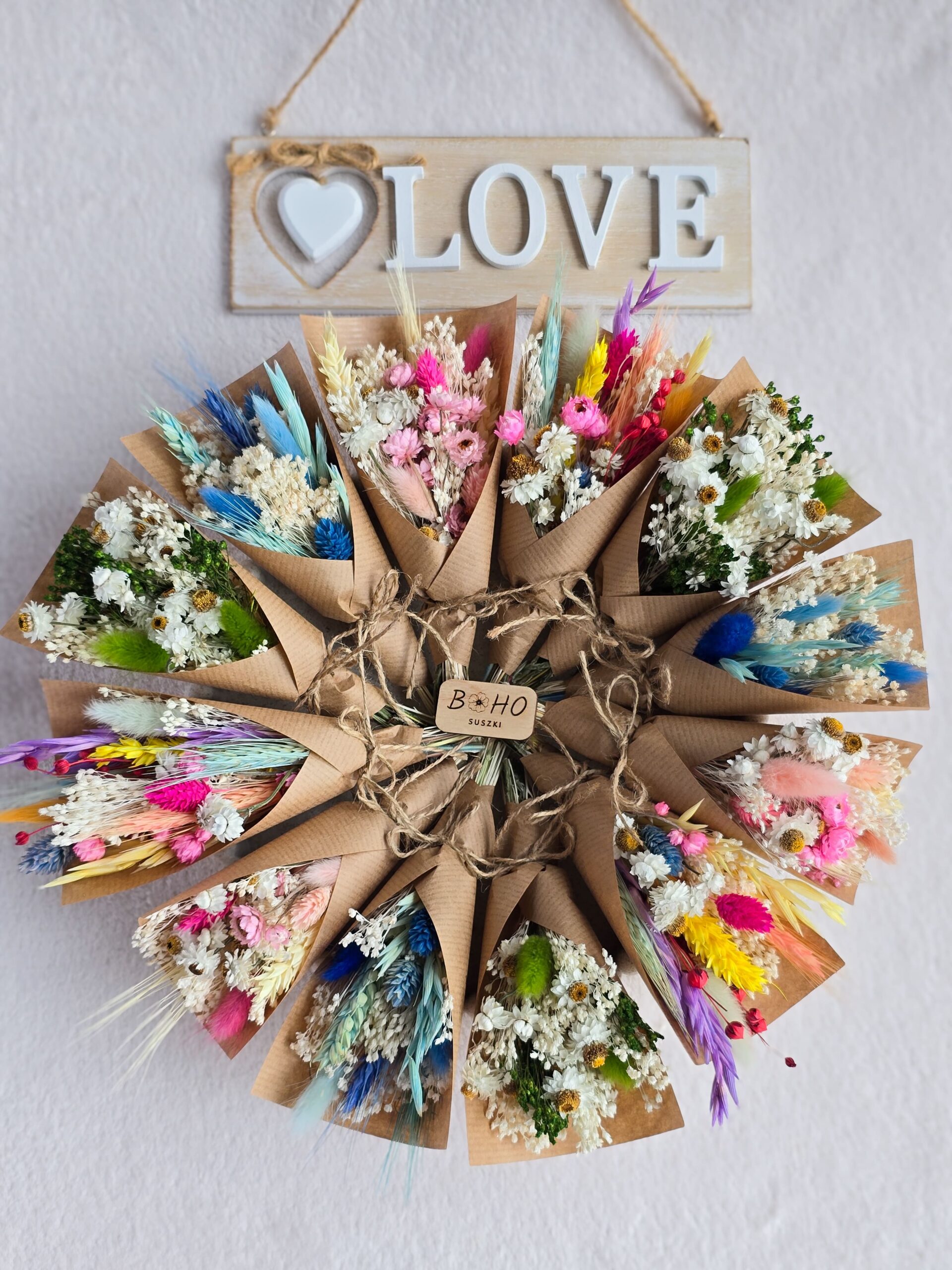 Kolorowe mini bukieciki z suszonych kwiatów owinięte w papier kraft jako forma podziękowania dla gości