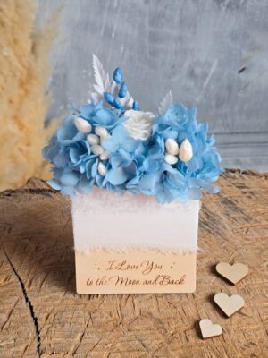 Butonierka ślubna wkładana do kieszonki z suszonymi i stabilizowanymi kwiatami w niebiesko-białej kolorystyce oraz z grawerowanym napisem I Love You to the Moon and Back